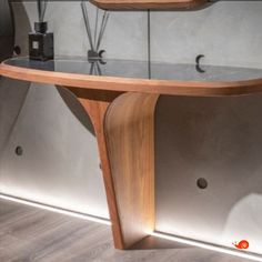 a curved wooden table with glass shelves on the wall and vases in front of it