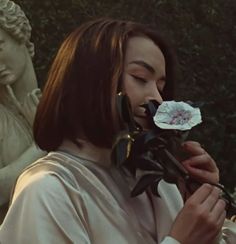 a woman holding a flower in front of her face