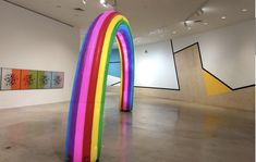 an art gallery with colorful sculptures and paintings on the walls, including a rainbow - colored arch