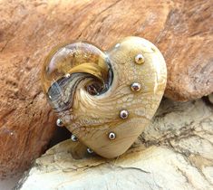 a heart shaped glass object sitting on top of a wooden piece with rivets