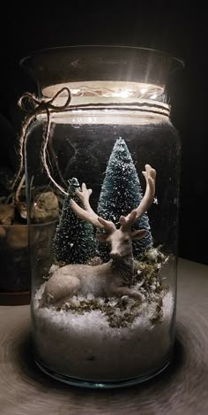 a glass jar filled with snow and a deer figurine