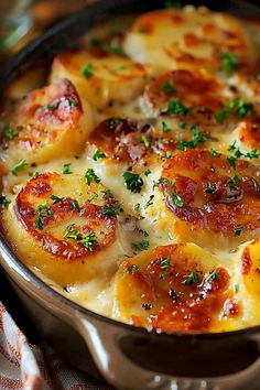 a close up of a pan of food with cheese and ham on top, garnished with parsley