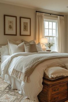 a large bed sitting under a window next to a wooden trunk with pillows on it