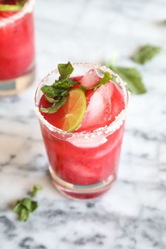 two glasses filled with watermelon and limeade on top of a marble table