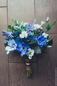 a bouquet of blue and white flowers sitting on top of a wooden table