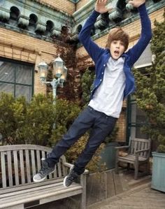 a boy jumping on a bench in front of a building