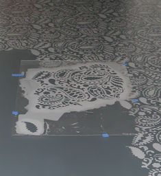 the floor is being painted with black and white designs on it's surface, as well as blue tape