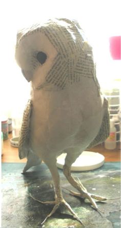 a bird is standing on the table in front of some paint and paper machs