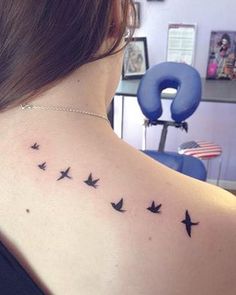 a woman's back shoulder tattoo with birds flying in the sky on her left side