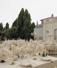 the table is set with white flowers and place settings for an elegant dinner party or reception