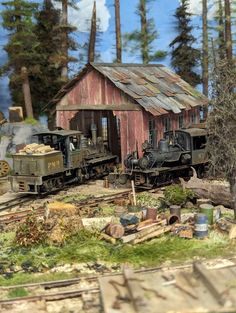 an old model train set up in front of a small red building with a tin roof