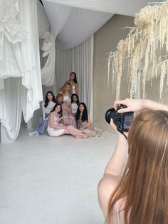 a group of women sitting on the floor in front of a white backdrop taking pictures