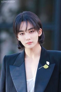 the young man is wearing a suit and flower brooch