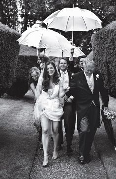 a group of people walking down a sidewalk with umbrellas over their heads in black and white