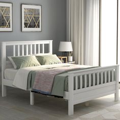 a white bed sitting in a bedroom on top of a hard wood floor next to a window