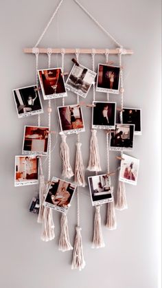 a wall hanging with pictures and tassels attached to the strings, on top of a white wall