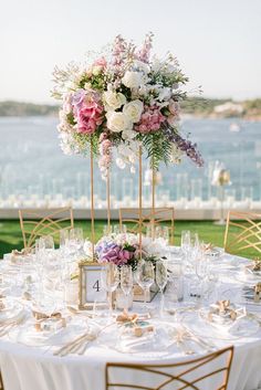 a table set up with flowers and wine glasses for a wedding reception at the waterfront