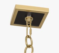 a golden chandelier hanging from a chain with a black square light fixture in the middle