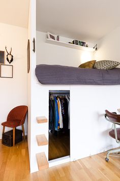 a loft bed is built into the side of a white wall in a small room