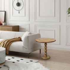 a white couch sitting next to a table on top of a hard wood floor in a living room