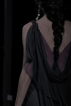 the back of a woman's dress with long black hair and large earrings on her head