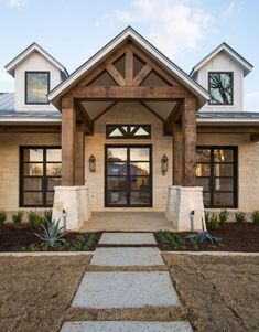 the front entrance to a home with stone steps leading up to it and two large windows