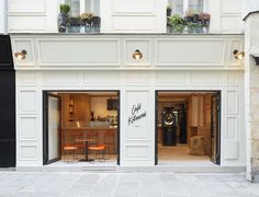 a store front with two chairs and tables in the doorway, on a city street