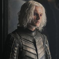 a man with white hair wearing armor in a dark room