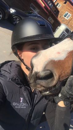 a woman wearing a helmet is petting a horse