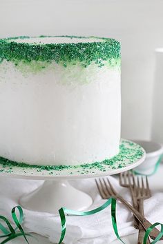 a white cake with green sprinkles and a fork next to it on a plate