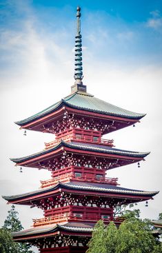 a tall red pagoda sitting next to a lush green forest