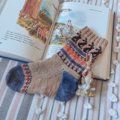 an open book with two knitted socks and a rabbit figurine