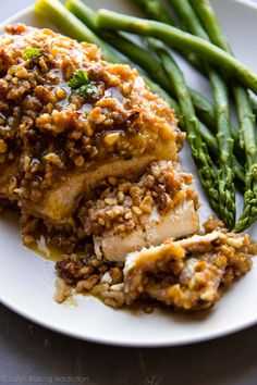 a white plate topped with meat and asparagus