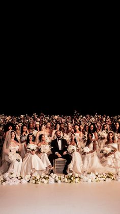 a large group of people dressed in wedding gowns and tuxedos posing for a photo