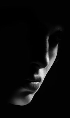 a black and white photo of a woman's face in the dark with her eyes closed