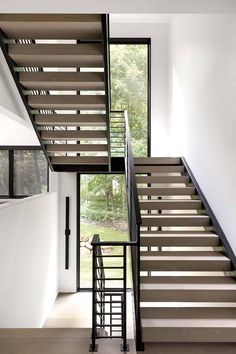 the stairs in this modern house are made of wood and metal, with black handrails