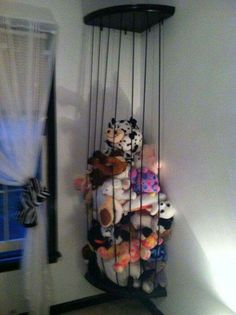 a bunch of stuffed animals are hanging from the ceiling in a room with white walls