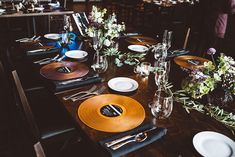 the table is set with plates, silverware and flowers in vases on it