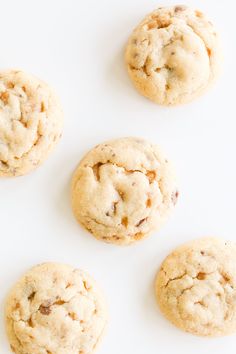 four chocolate chip cookies arranged on a white surface with one broken in half and the other uncooked