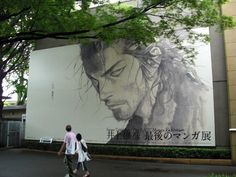 two people walking past a large advertisement on the side of a building