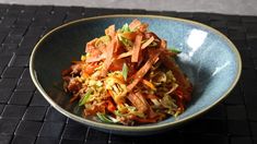 a blue bowl filled with food on top of a table