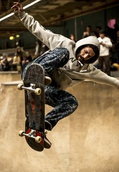 a skateboarder in mid air doing a trick at a skate park while people watch