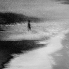 a blurry photo of a person walking on the beach near the water's edge