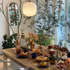 a wooden table topped with lots of food next to a tall vase filled with flowers