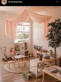 a child's playroom with wooden furniture and pink drapes over the windows