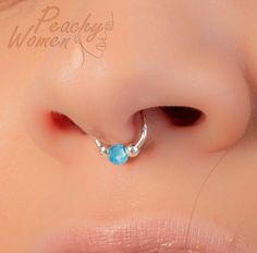 a woman's nose with a blue stone in the middle and a silver nose ring attached to it