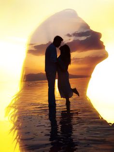 a man and woman standing in the water at sunset