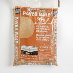 a bag of paper base sitting on top of a white wall next to a wooden stick