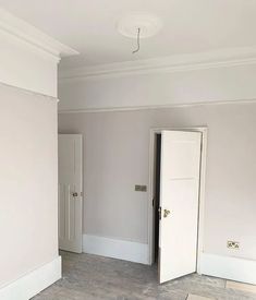 an empty room with white walls and wood floors