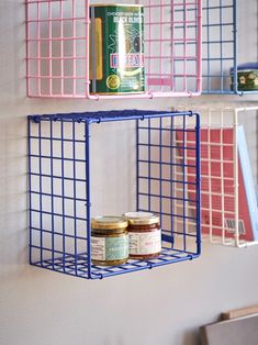 two blue metal shelves with jars and cans hanging on the wall next to each other